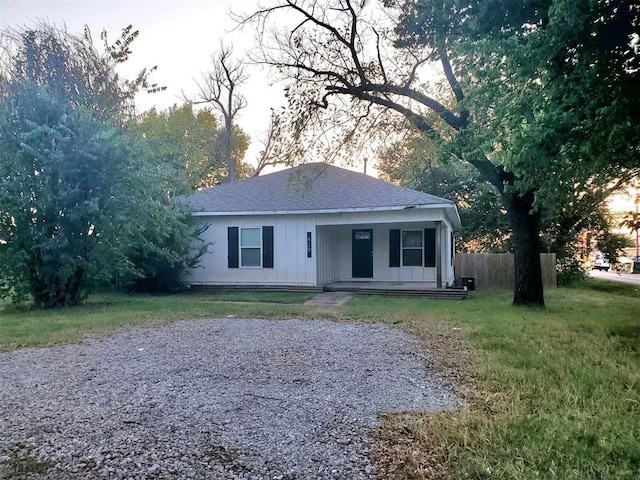 ranch-style house featuring covered porch and a front yard