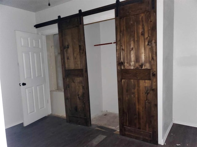 interior space with dark hardwood / wood-style floors, a barn door, and a closet