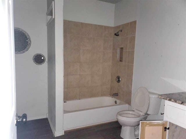 full bathroom featuring vanity, tiled shower / bath combo, and toilet