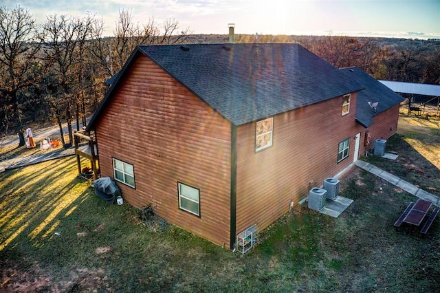 view of side of home with central AC and a yard