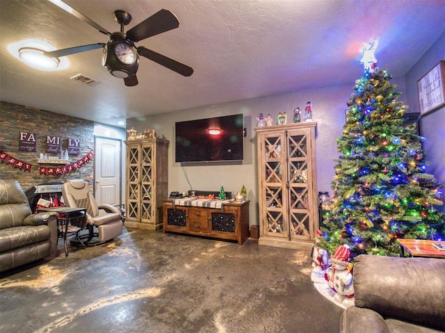 living room with ceiling fan, concrete flooring, and a textured ceiling