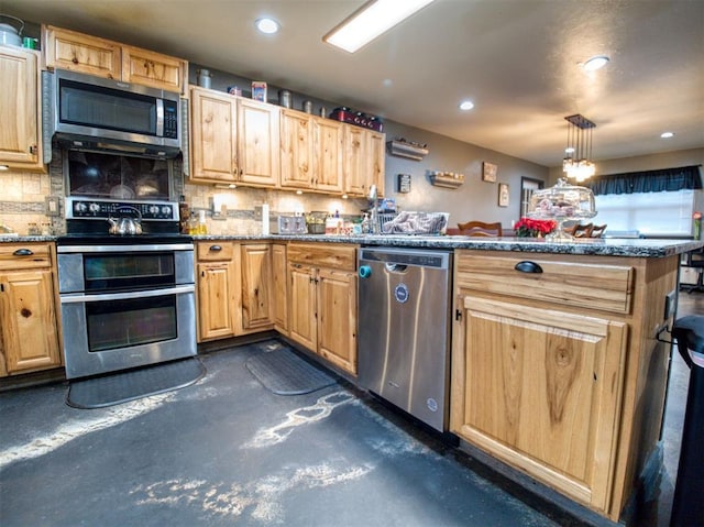 kitchen featuring pendant lighting, dark stone countertops, appliances with stainless steel finishes, tasteful backsplash, and kitchen peninsula