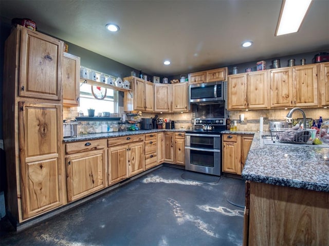 kitchen with backsplash, dark stone countertops, sink, and appliances with stainless steel finishes