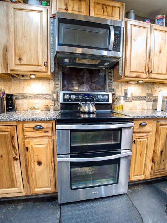 kitchen with backsplash, light stone counters, and stainless steel appliances