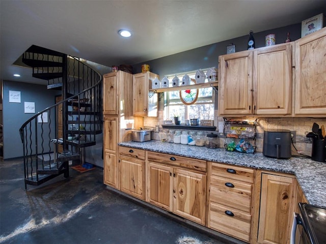 kitchen featuring light stone countertops, light brown cabinetry, backsplash, and range