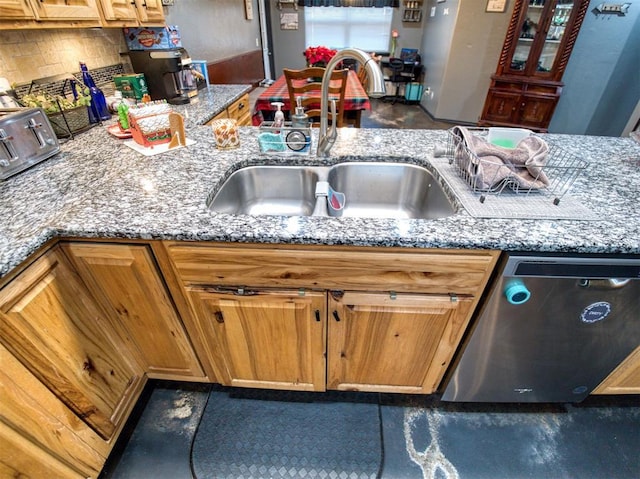 kitchen featuring light stone countertops, sink, and stainless steel dishwasher