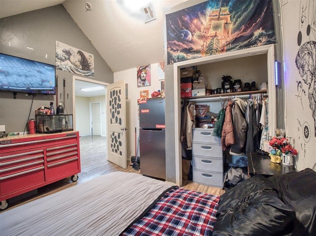 bedroom with a closet, hardwood / wood-style floors, and lofted ceiling