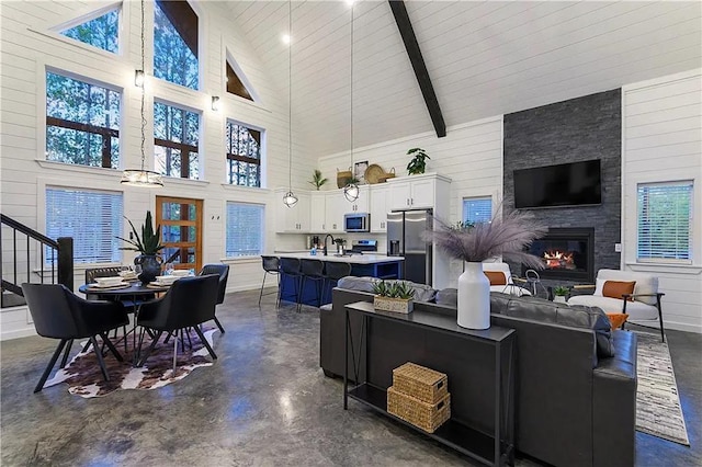 living room with beamed ceiling, plenty of natural light, a large fireplace, and high vaulted ceiling