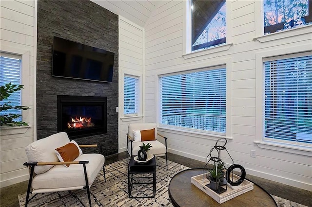 living area with a fireplace and a towering ceiling