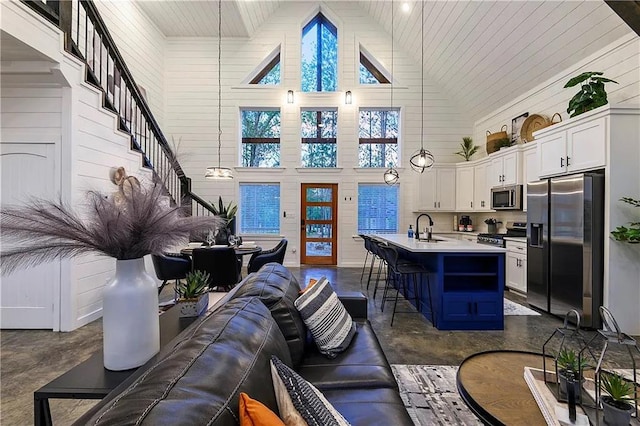 living room with wood walls, sink, and high vaulted ceiling