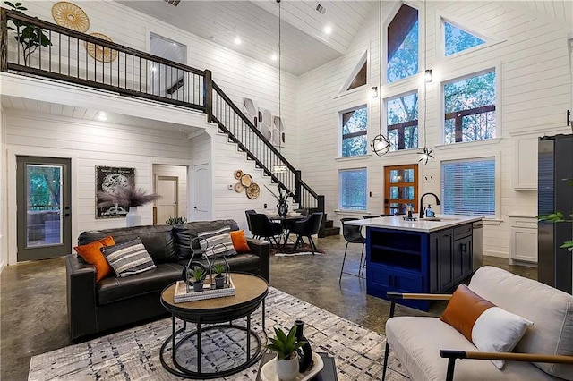 living room with wood walls, sink, and high vaulted ceiling