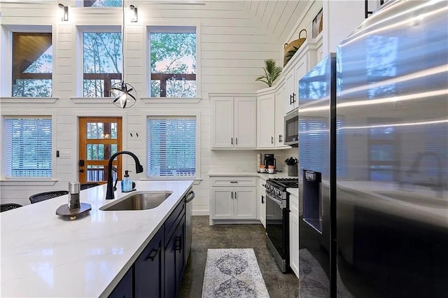 kitchen featuring stainless steel appliances, white cabinetry, plenty of natural light, and sink