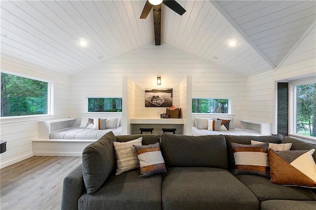 bedroom with light wood-type flooring, wood ceiling, ceiling fan, lofted ceiling with beams, and wood walls