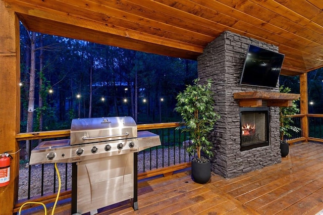 wooden deck featuring an outdoor stone fireplace and grilling area