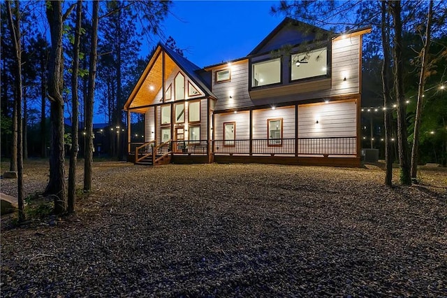 back house at twilight with covered porch and central AC