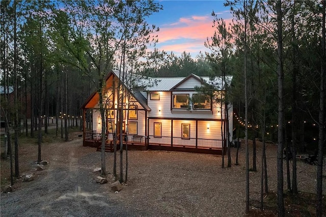 back house at dusk featuring a porch