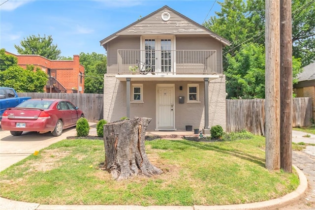 view of property with a balcony and a front lawn