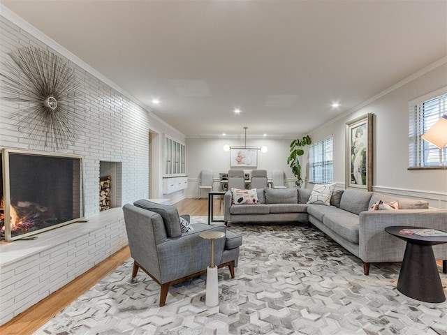 living room with a brick fireplace, light hardwood / wood-style floors, and ornamental molding