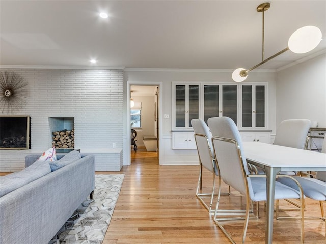 dining room featuring ornamental molding, a fireplace, and light hardwood / wood-style flooring