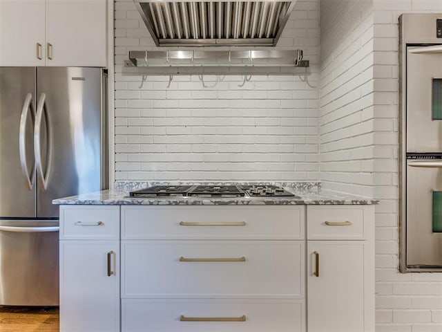 kitchen featuring wall chimney exhaust hood, white cabinets, and stainless steel appliances