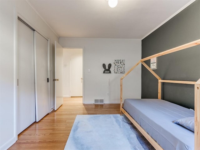 bedroom featuring light hardwood / wood-style flooring, a closet, and crown molding