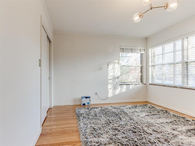 interior space featuring an inviting chandelier, light hardwood / wood-style flooring, and ornamental molding