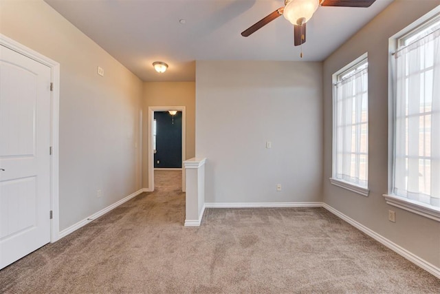 carpeted empty room featuring ceiling fan and a wealth of natural light