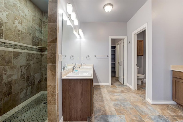 bathroom with a tile shower, vanity, and toilet