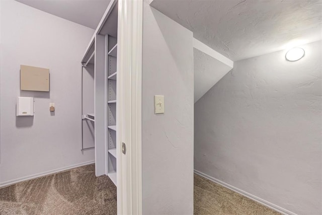 spacious closet with dark carpet and vaulted ceiling