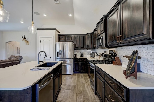 kitchen featuring sink, light hardwood / wood-style flooring, pendant lighting, stainless steel appliances, and backsplash