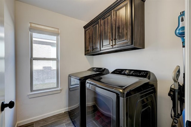 clothes washing area with dark wood-type flooring, cabinets, and separate washer and dryer