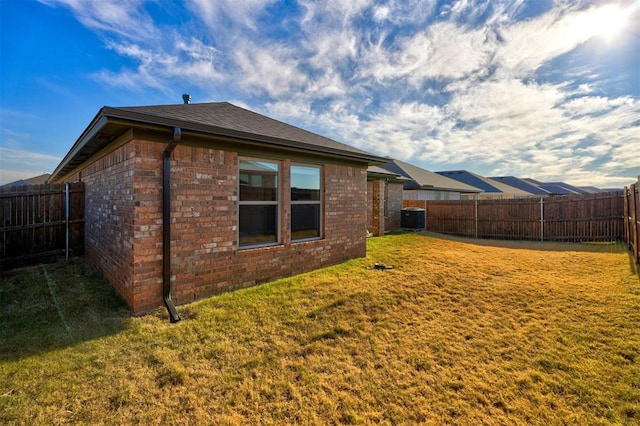 rear view of house featuring cooling unit and a yard