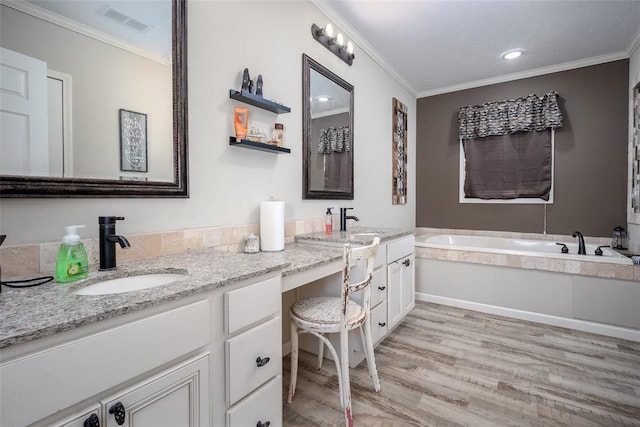 bathroom with crown molding, vanity, a bathing tub, and hardwood / wood-style floors