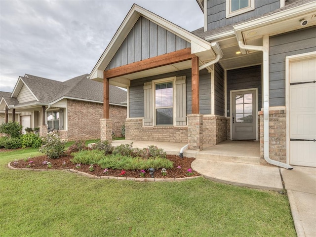 doorway to property featuring a lawn, a porch, a garage, and roof with shingles