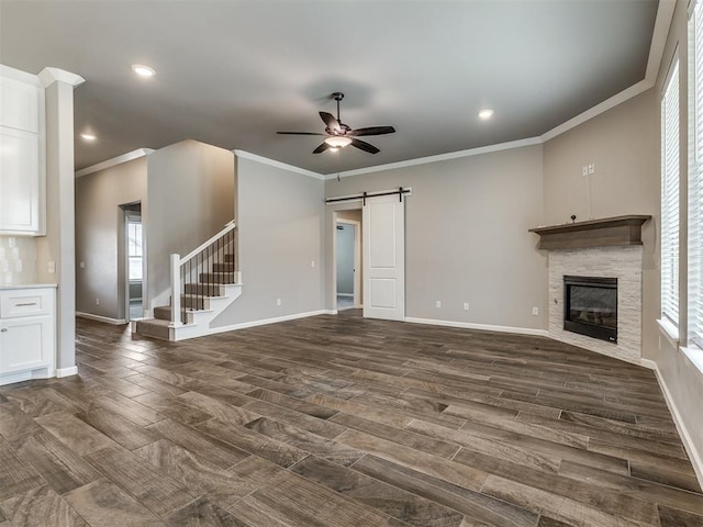 unfurnished living room featuring a barn door, baseboards, and ceiling fan