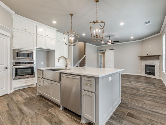 kitchen with visible vents, a sink, stainless steel appliances, a barn door, and open floor plan