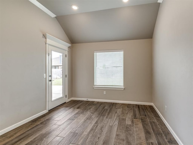 unfurnished room featuring vaulted ceiling, wood finished floors, and baseboards