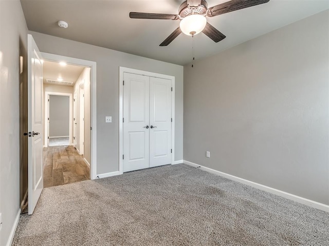 unfurnished bedroom with a closet, baseboards, ceiling fan, and carpet flooring