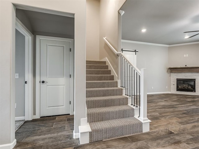 stairway with wood finished floors, recessed lighting, a barn door, crown molding, and baseboards