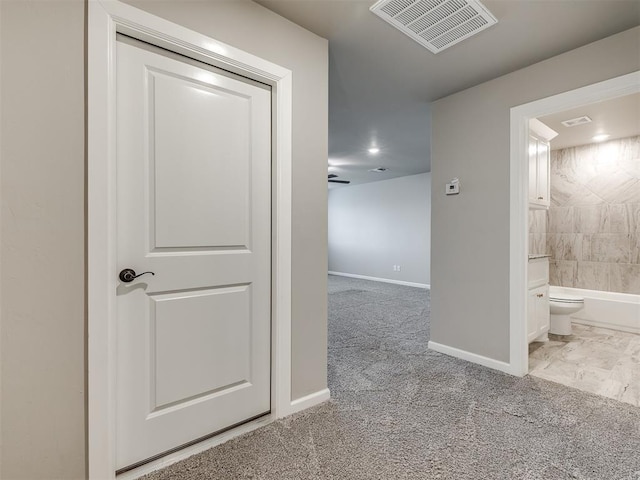 hall featuring visible vents, baseboards, and carpet floors