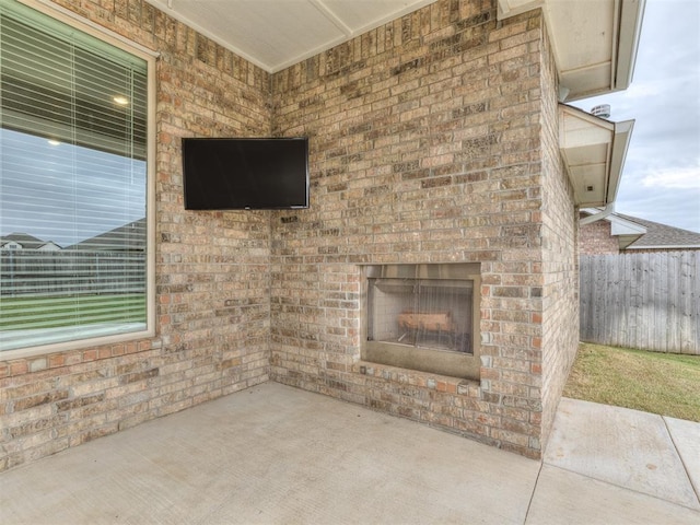 view of patio with fence and an outdoor brick fireplace