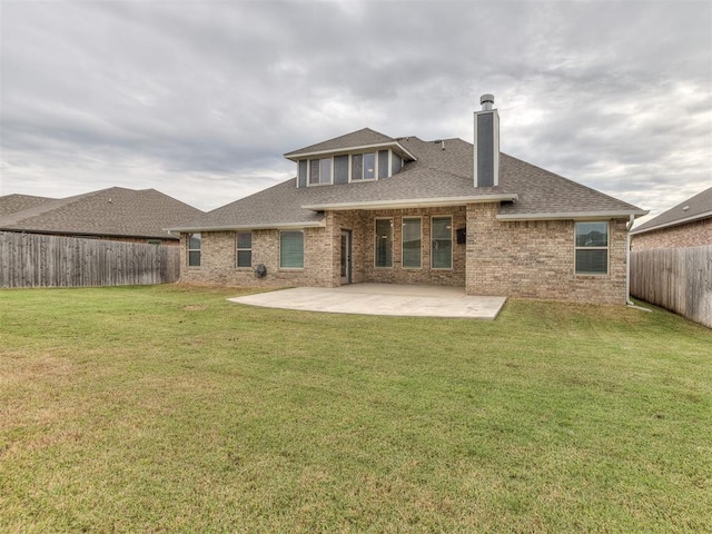 rear view of property featuring roof with shingles, a yard, a fenced backyard, a patio area, and brick siding