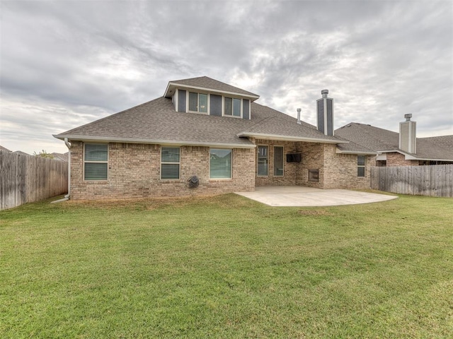 back of house with a patio, a lawn, a fenced backyard, and a shingled roof