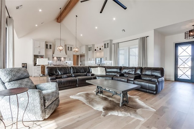 living room with beamed ceiling, a healthy amount of sunlight, light hardwood / wood-style floors, and high vaulted ceiling