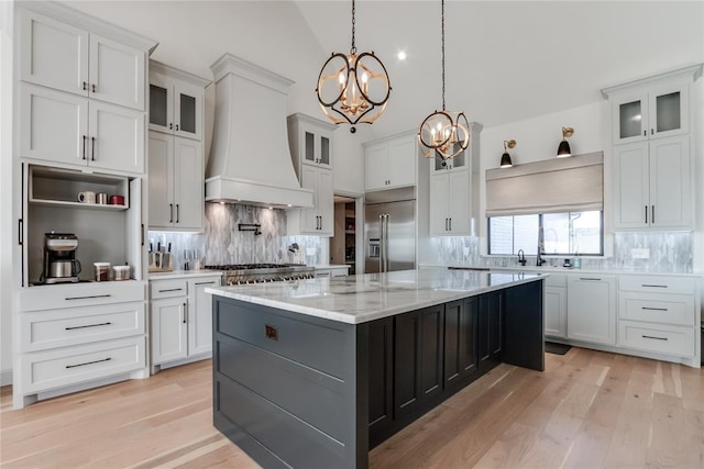 kitchen with premium range hood, tasteful backsplash, stainless steel built in refrigerator, a center island, and white cabinetry