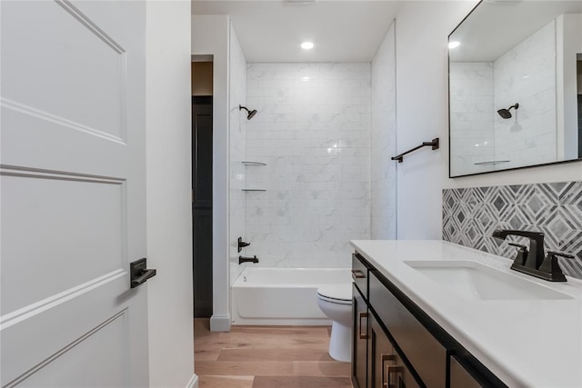 full bathroom with tasteful backsplash, vanity, tiled shower / bath combo, hardwood / wood-style flooring, and toilet