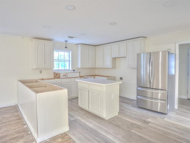 kitchen featuring light wood-type flooring, stainless steel fridge, a center island, and white cabinets