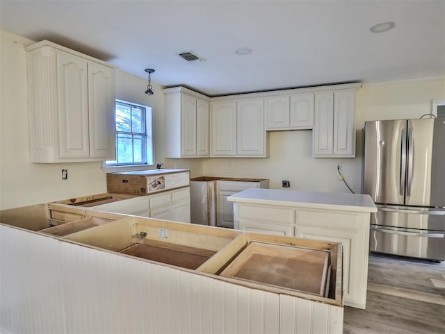 kitchen featuring light wood-type flooring, a center island, white cabinetry, and stainless steel refrigerator