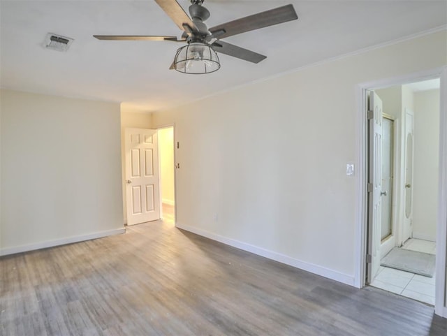 spare room featuring wood-type flooring, ceiling fan, and crown molding