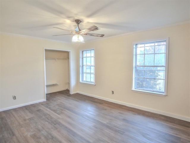 unfurnished bedroom with multiple windows, ceiling fan, wood-type flooring, and ornamental molding